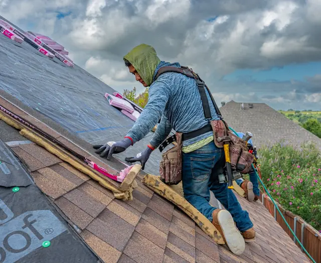 A roofer laying shingles